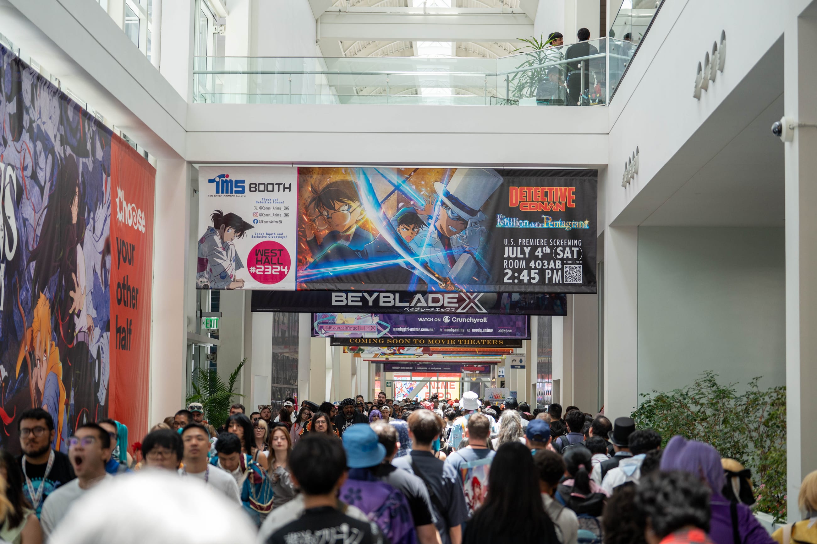 Crowded convention center concourse under a Beyblade X banner, attendees filling the walkway between booths